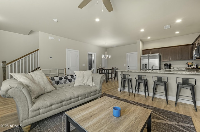 living room featuring sink, ceiling fan with notable chandelier, and light hardwood / wood-style floors