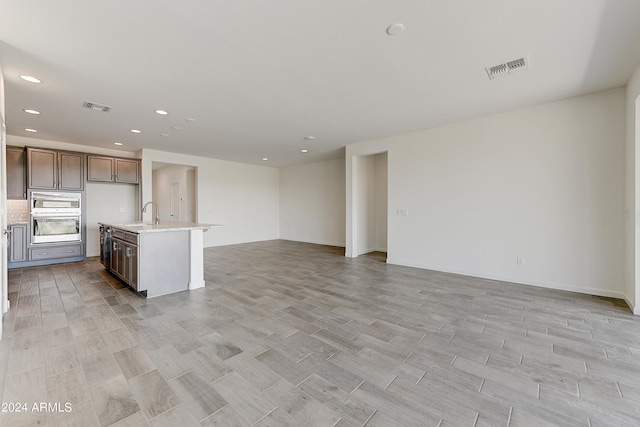 kitchen featuring an island with sink, light wood-type flooring, and sink