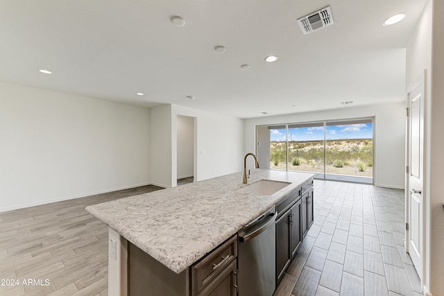 kitchen featuring dishwasher, light hardwood / wood-style flooring, a kitchen island with sink, and sink