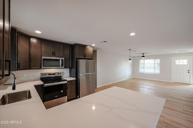 kitchen with ceiling fan, pendant lighting, sink, light hardwood / wood-style flooring, and appliances with stainless steel finishes