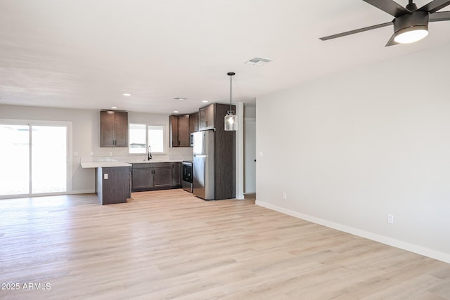 kitchen featuring ceiling fan, appliances with stainless steel finishes, decorative light fixtures, light wood-type flooring, and sink