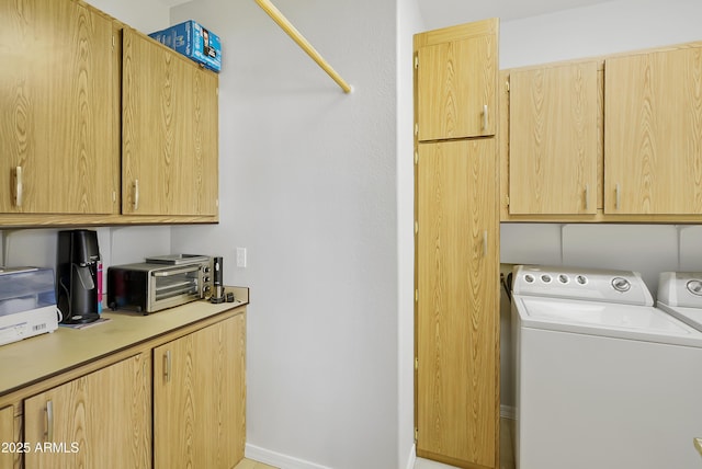 washroom featuring washing machine and dryer, a toaster, and cabinet space