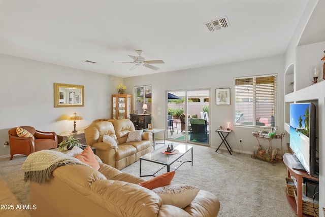 living room featuring visible vents, baseboards, light colored carpet, and a ceiling fan