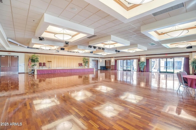 interior space featuring a tray ceiling, visible vents, and wood finished floors