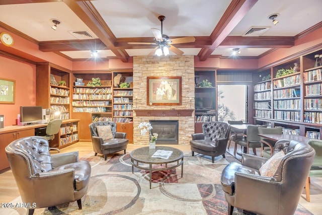 living area featuring visible vents, coffered ceiling, a stone fireplace, and a ceiling fan