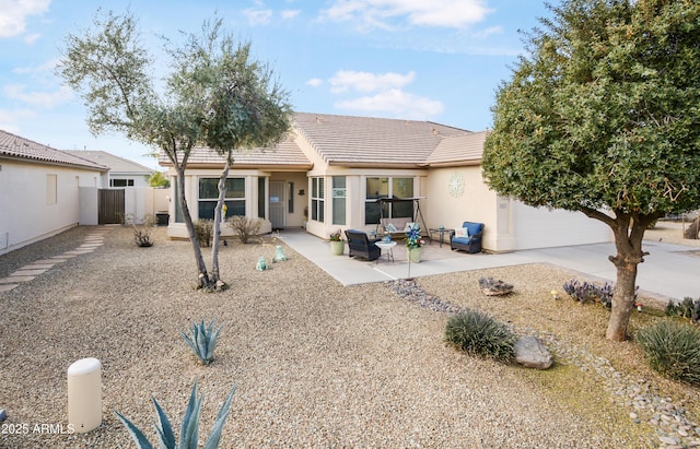 rear view of house featuring a patio, fence, stucco siding, concrete driveway, and a tiled roof