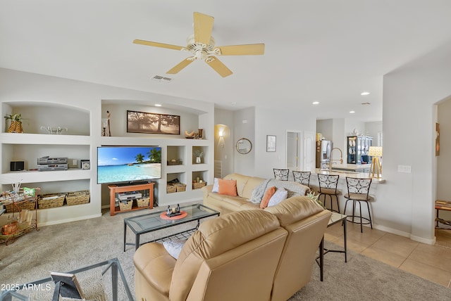 living room with tile patterned floors, visible vents, a ceiling fan, built in features, and carpet flooring