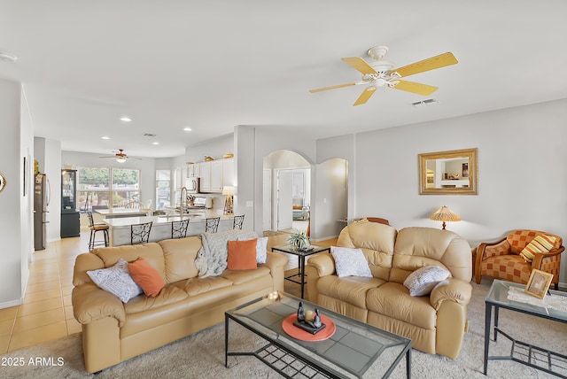 living area with visible vents, light tile patterned floors, recessed lighting, arched walkways, and a ceiling fan