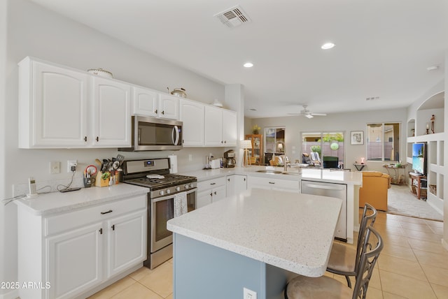 kitchen featuring visible vents, a peninsula, a sink, stainless steel appliances, and open floor plan