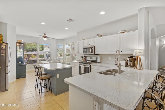 kitchen with visible vents, a ceiling fan, a sink, a kitchen breakfast bar, and appliances with stainless steel finishes