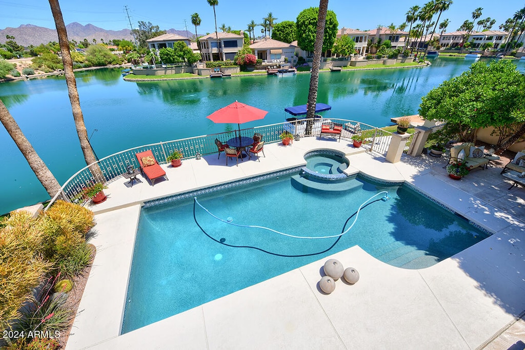 view of swimming pool featuring an in ground hot tub, a patio, and a water and mountain view