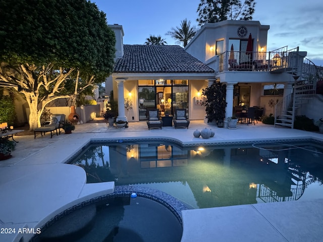 pool at dusk with an in ground hot tub and a patio area