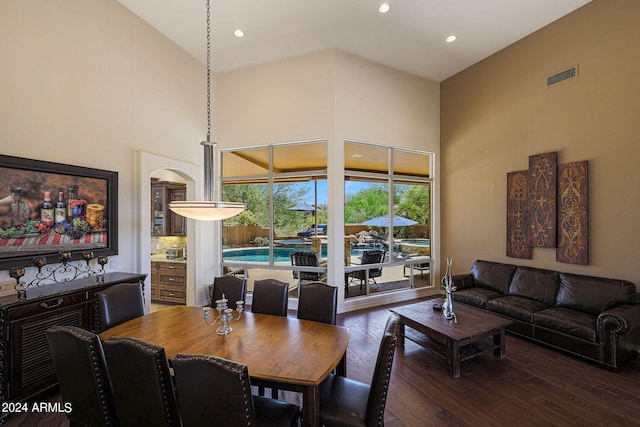 dining area with high vaulted ceiling and dark hardwood / wood-style flooring