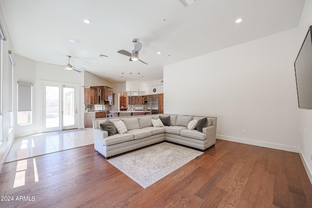 living room featuring vaulted ceiling, wood-type flooring, and ceiling fan