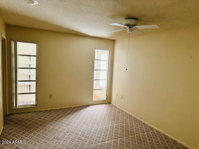 empty room with ceiling fan, a textured ceiling, and carpet floors