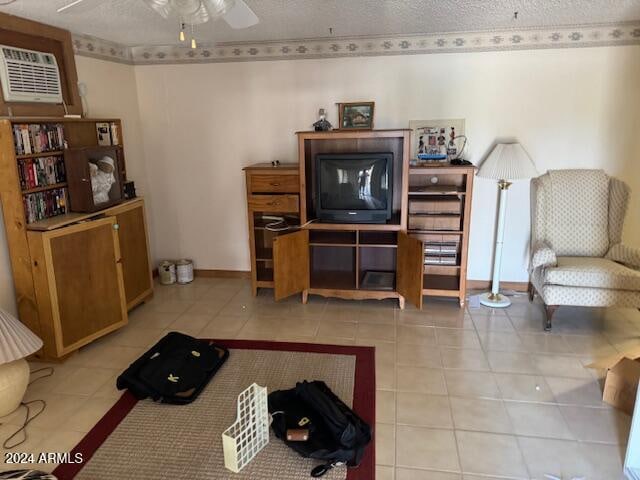 living room with light tile patterned flooring, ceiling fan, a textured ceiling, and an AC wall unit