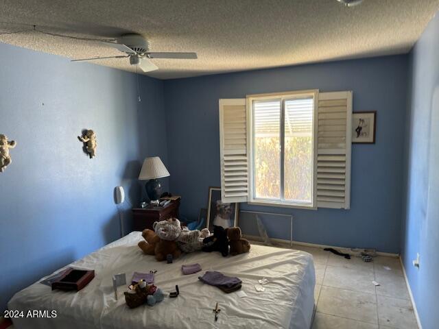 bedroom with a textured ceiling, ceiling fan, and light tile patterned floors