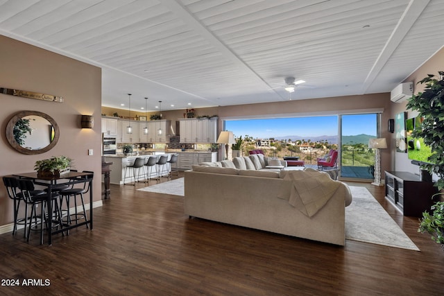 living room featuring a mountain view, dark hardwood / wood-style floors, a wall unit AC, and ceiling fan