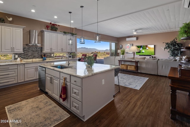 kitchen featuring white cabinetry, wall chimney range hood, sink, and an island with sink