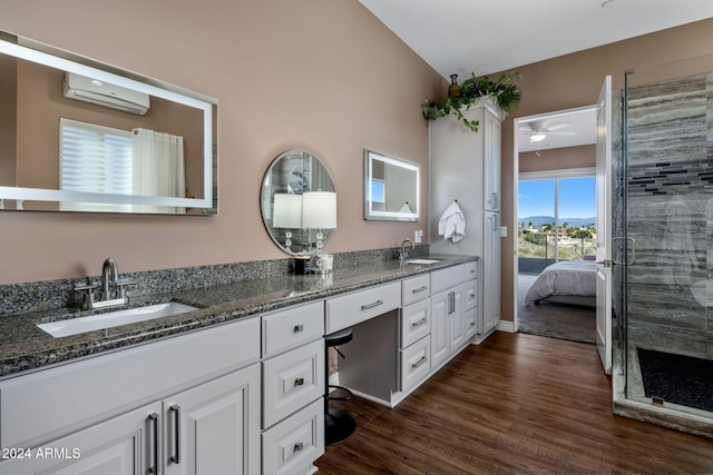 bathroom with ceiling fan, an AC wall unit, vaulted ceiling, vanity, and hardwood / wood-style flooring