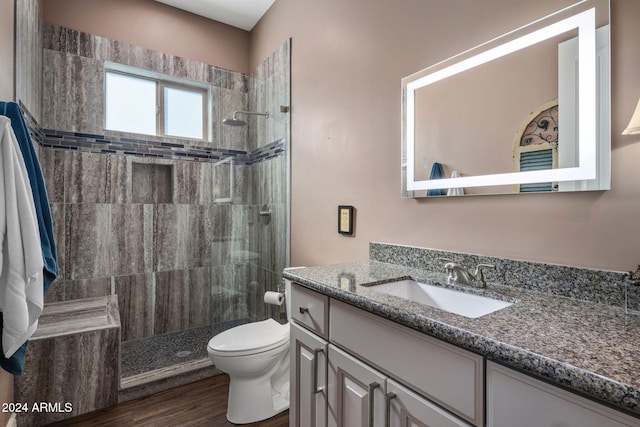 bathroom with tiled shower, wood-type flooring, vanity, and toilet