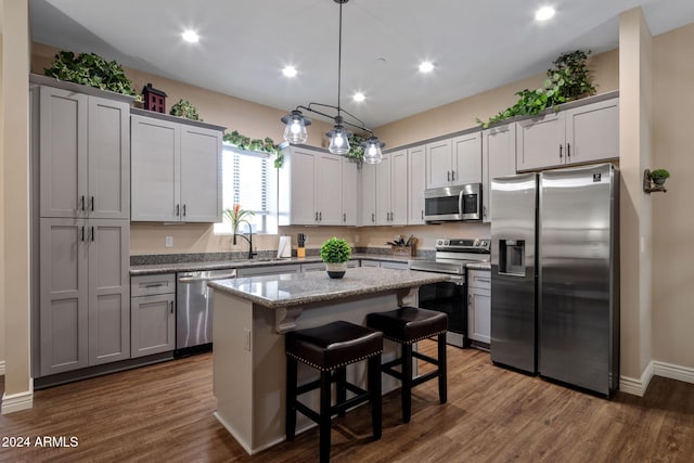 kitchen with gray cabinetry, a center island, a kitchen breakfast bar, hanging light fixtures, and stainless steel appliances