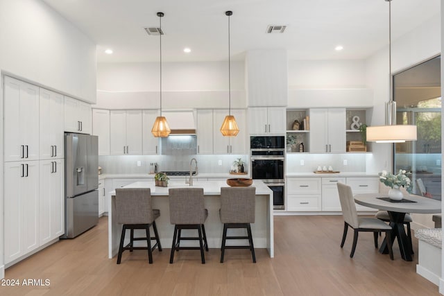 kitchen with backsplash, stainless steel fridge with ice dispenser, white cabinets, and an island with sink