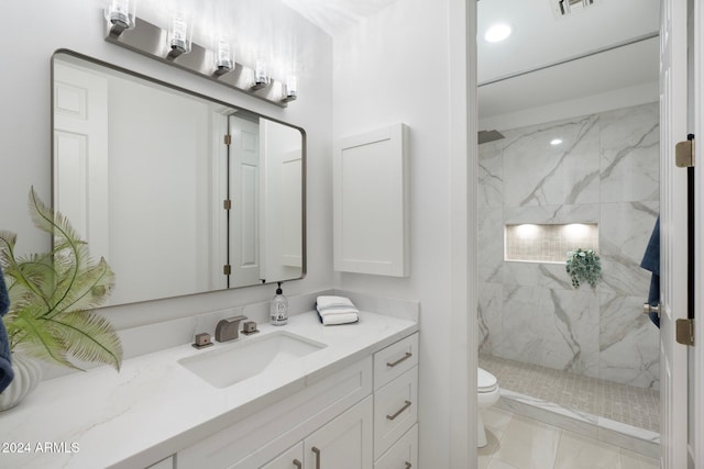 bathroom with tile patterned flooring, toilet, vanity, and tiled shower