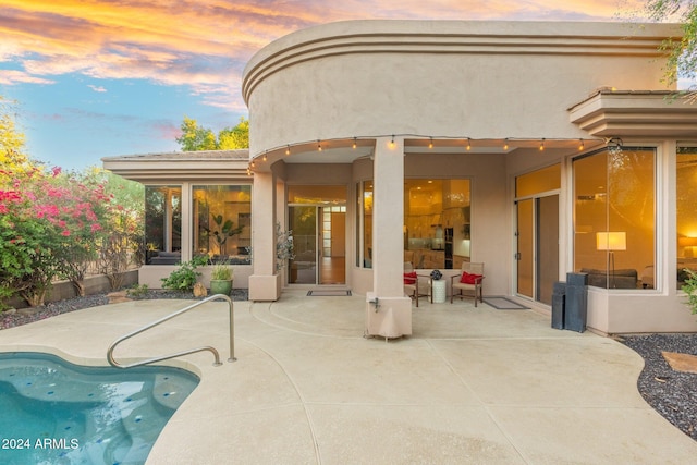 back house at dusk featuring a patio area and an outdoor living space