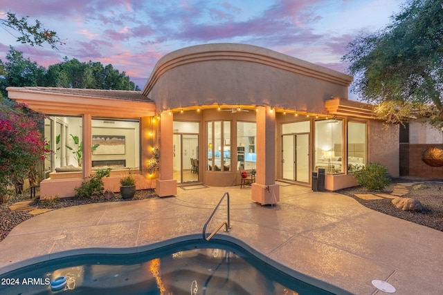 back house at dusk with a patio area