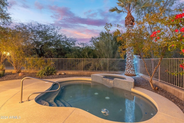 pool at dusk featuring an in ground hot tub