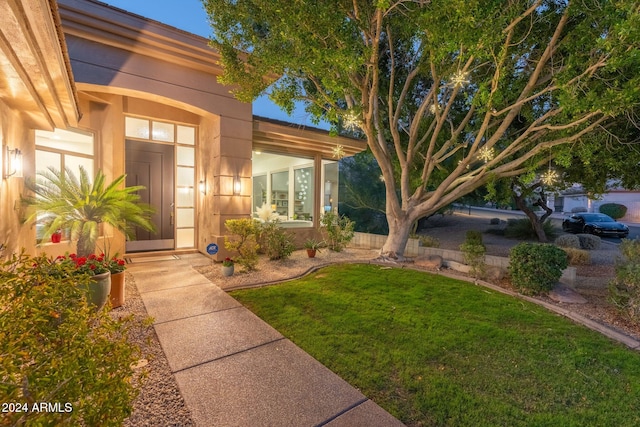 view of exterior entry with a lawn