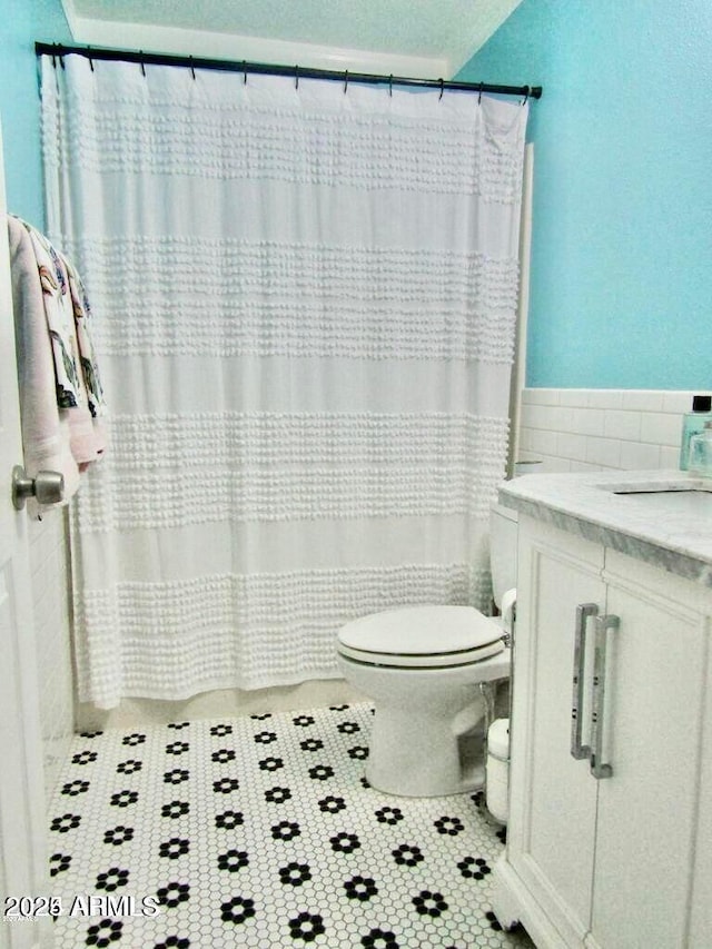 bathroom featuring tile patterned flooring, vanity, tile walls, and toilet