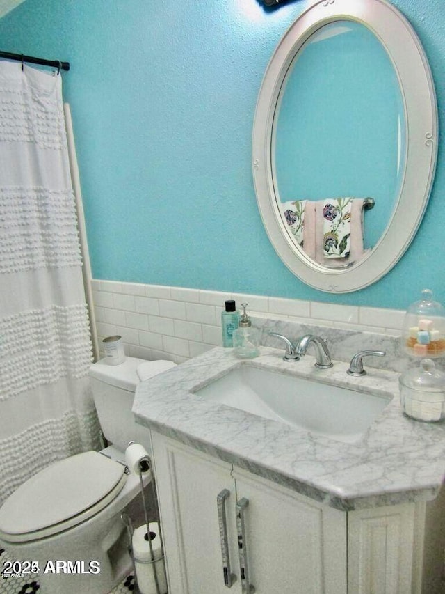 bathroom with a shower with curtain, vanity, toilet, and tile walls