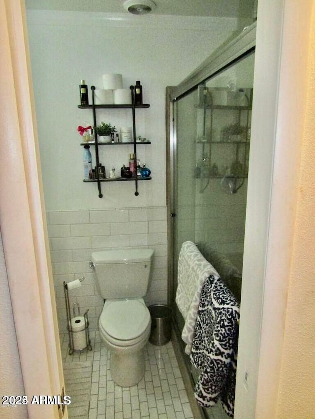 bathroom with toilet, tile walls, and walk in shower