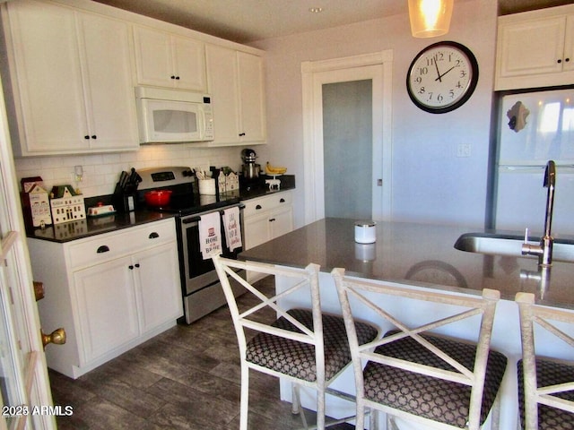 kitchen featuring sink, white appliances, white cabinetry, tasteful backsplash, and dark hardwood / wood-style flooring