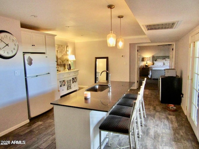 kitchen featuring sink, a breakfast bar area, white cabinets, white fridge, and a center island