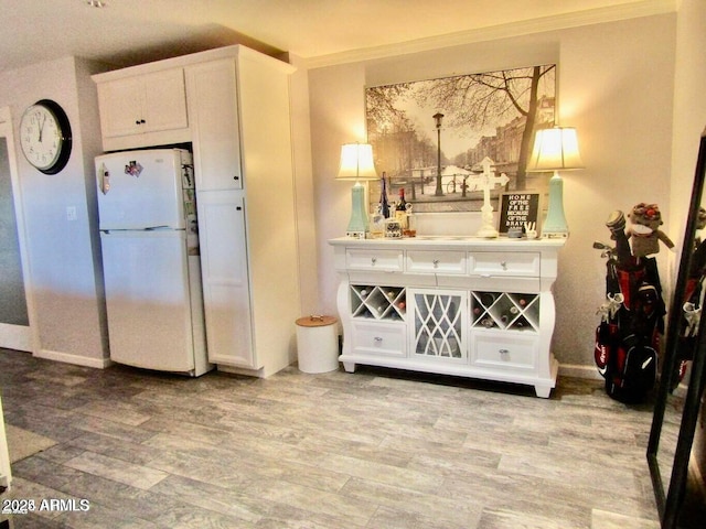 interior space with white cabinetry, white fridge, crown molding, and light wood-type flooring