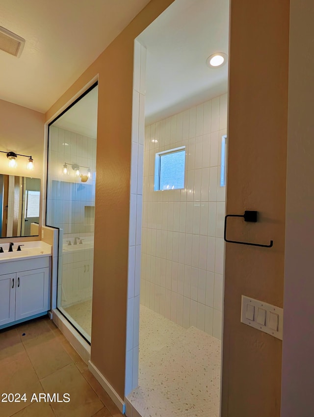 bathroom featuring vanity, a tile shower, and tile patterned floors