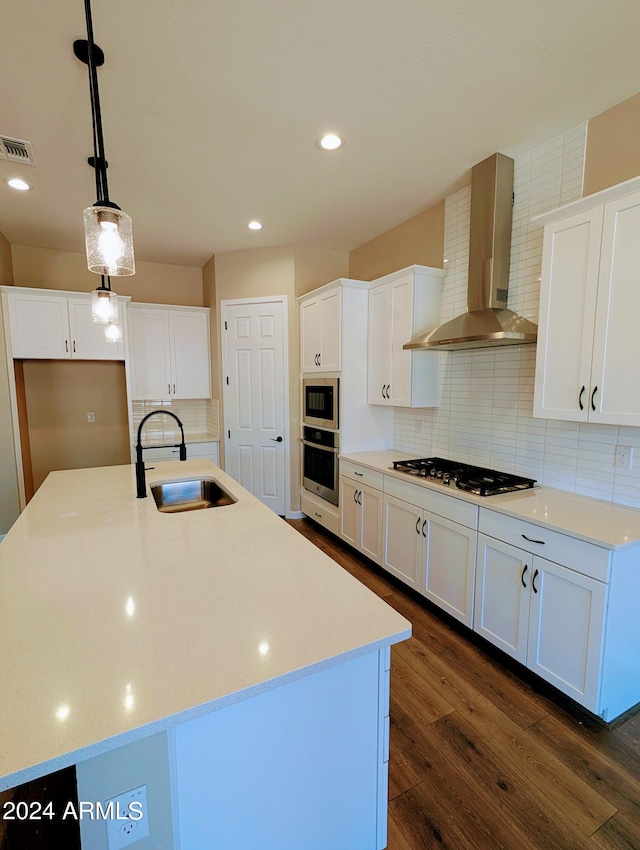 kitchen featuring wall chimney exhaust hood, a kitchen island with sink, sink, and stainless steel appliances