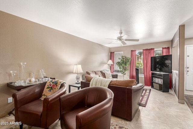 living room with ceiling fan, light tile patterned flooring, and a textured ceiling