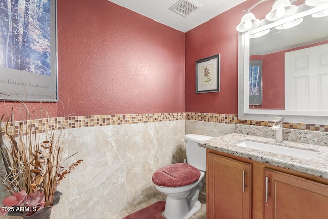 bathroom with tile walls, vanity, and toilet