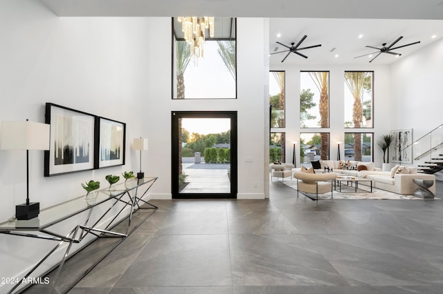 entrance foyer featuring a wealth of natural light, ceiling fan with notable chandelier, and a towering ceiling