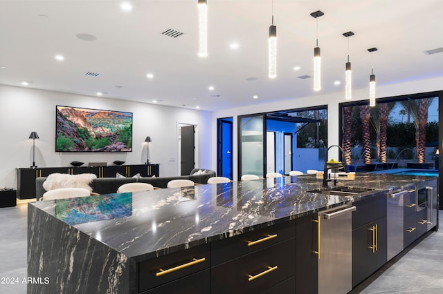 kitchen featuring a spacious island, dark stone counters, pendant lighting, and sink