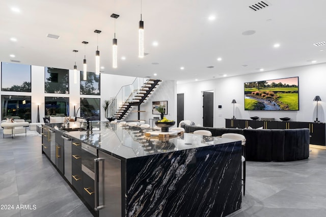 kitchen with a large island, a breakfast bar area, dark stone countertops, decorative light fixtures, and sink