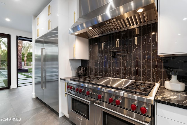 kitchen featuring white cabinetry, wall chimney range hood, high end appliances, and decorative backsplash