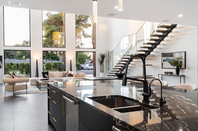 kitchen featuring dark stone countertops, white cabinetry, and sink