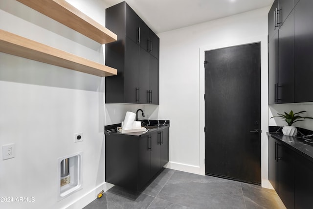 laundry area featuring electric dryer hookup, sink, and dark tile patterned floors