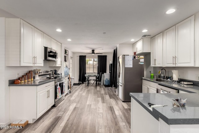 11132 W Indiana Ave, Youngtown, AZ 85363 - kitchen with stainless steel appliances, dark countertops, a sink, light wood finished floors, and ceiling fan