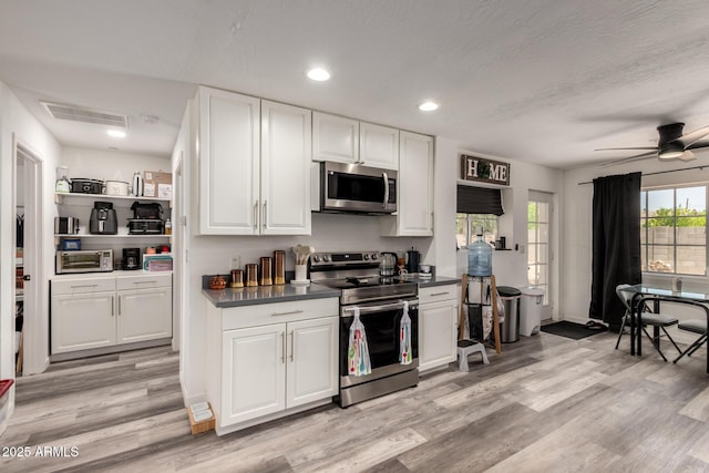 11132 W Indiana Ave, Youngtown, AZ 85363 - kitchen featuring stainless steel appliances, white cabinetry, dark countertops, light wood-style floors, and recessed lighting